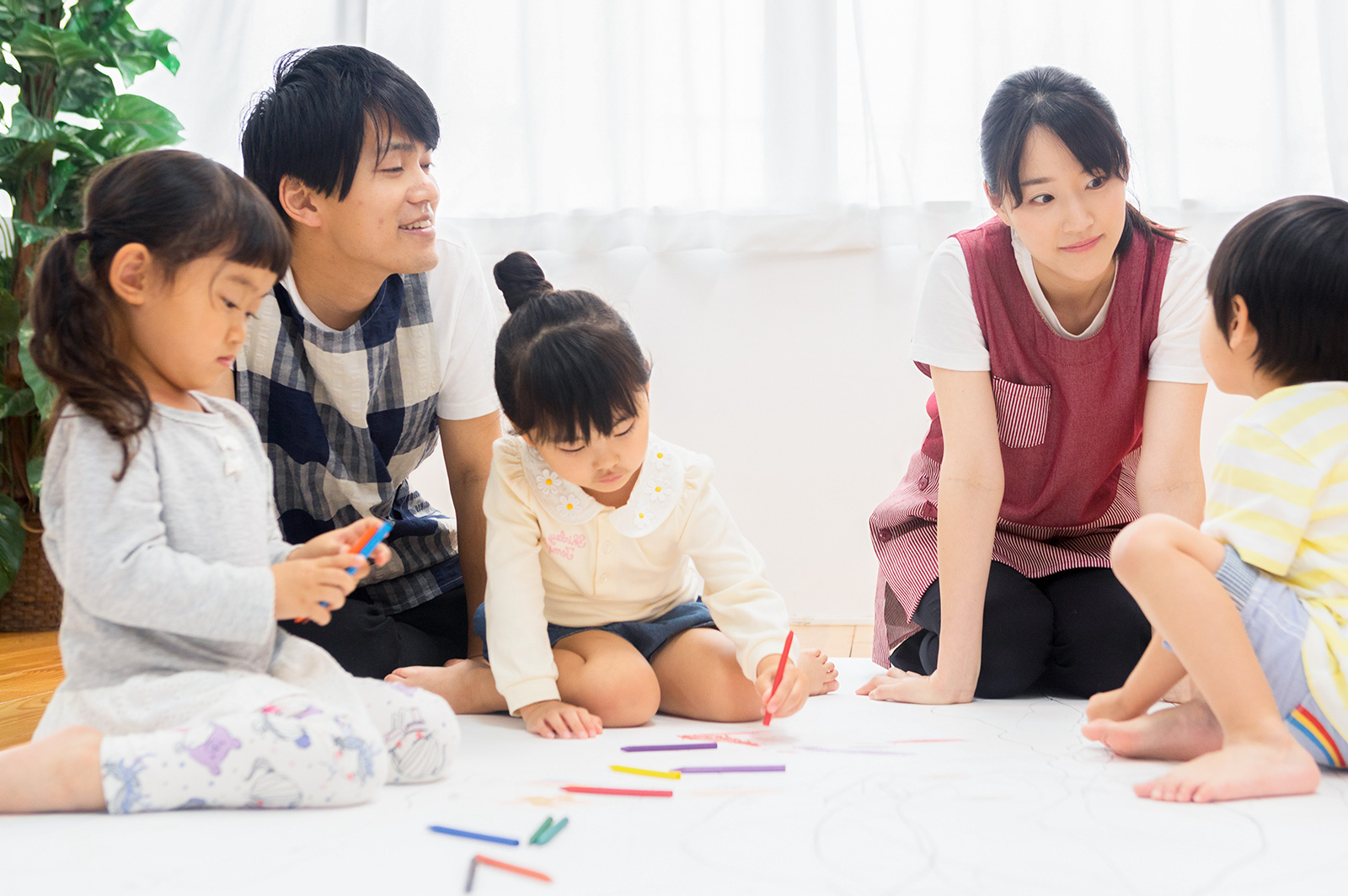 保育士たちと一緒にお絵描きをする子どもたち