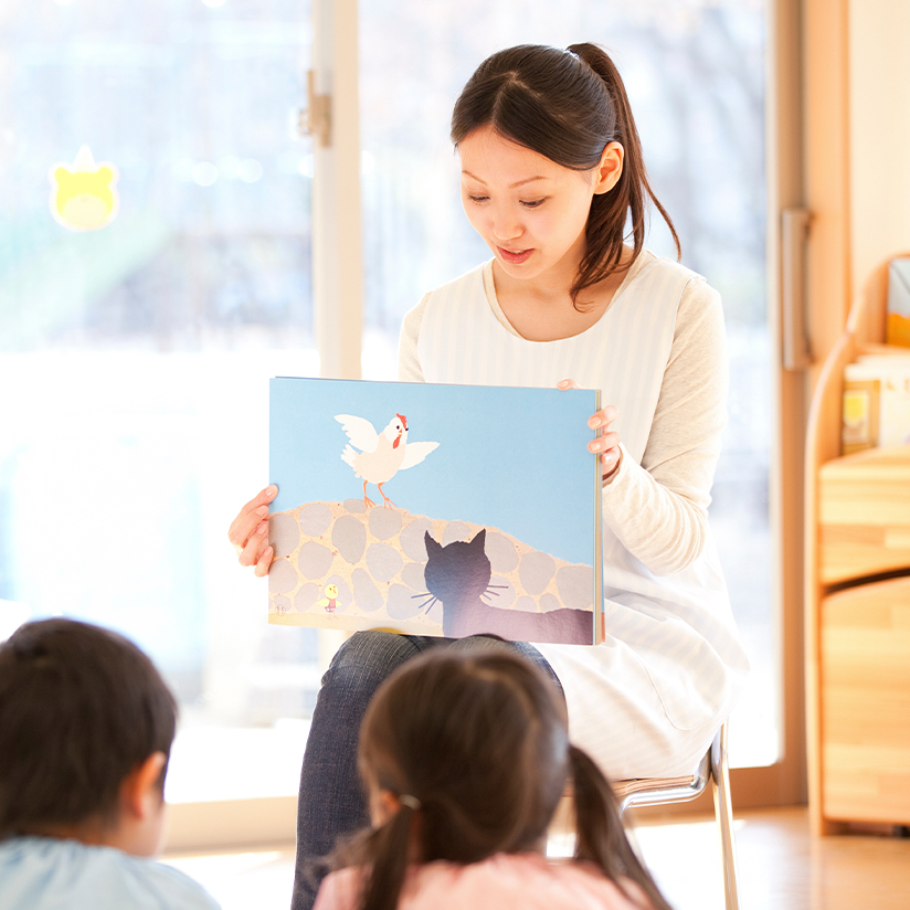 子どもたちに絵本の読み聞かせをする保育士