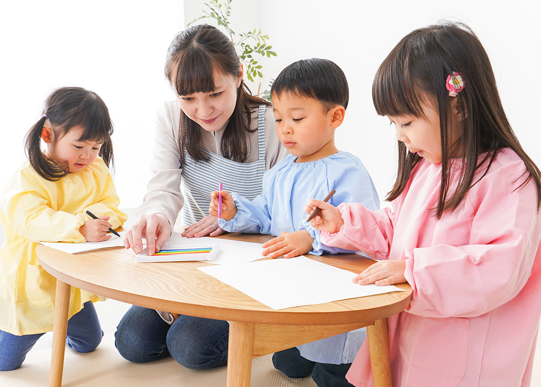 保育士と一緒にお絵描きをする子どもたち